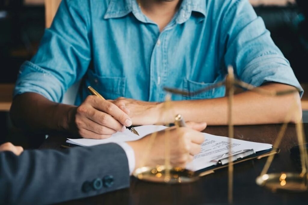A man obtaining legal representation from a lawyer, signing the agreement forms