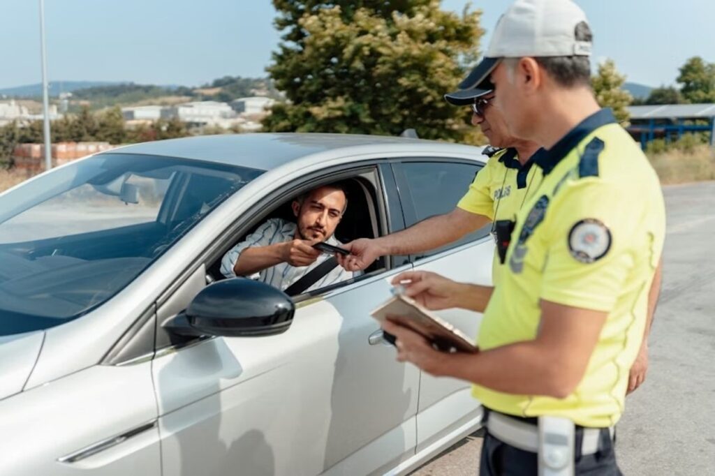 A man pulled over by traffic officers, handing over his license and registration.
